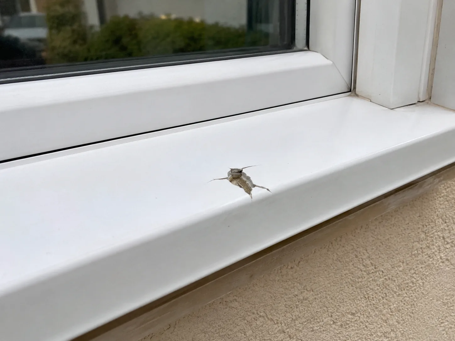 Impact damage to a white uPVC window cill