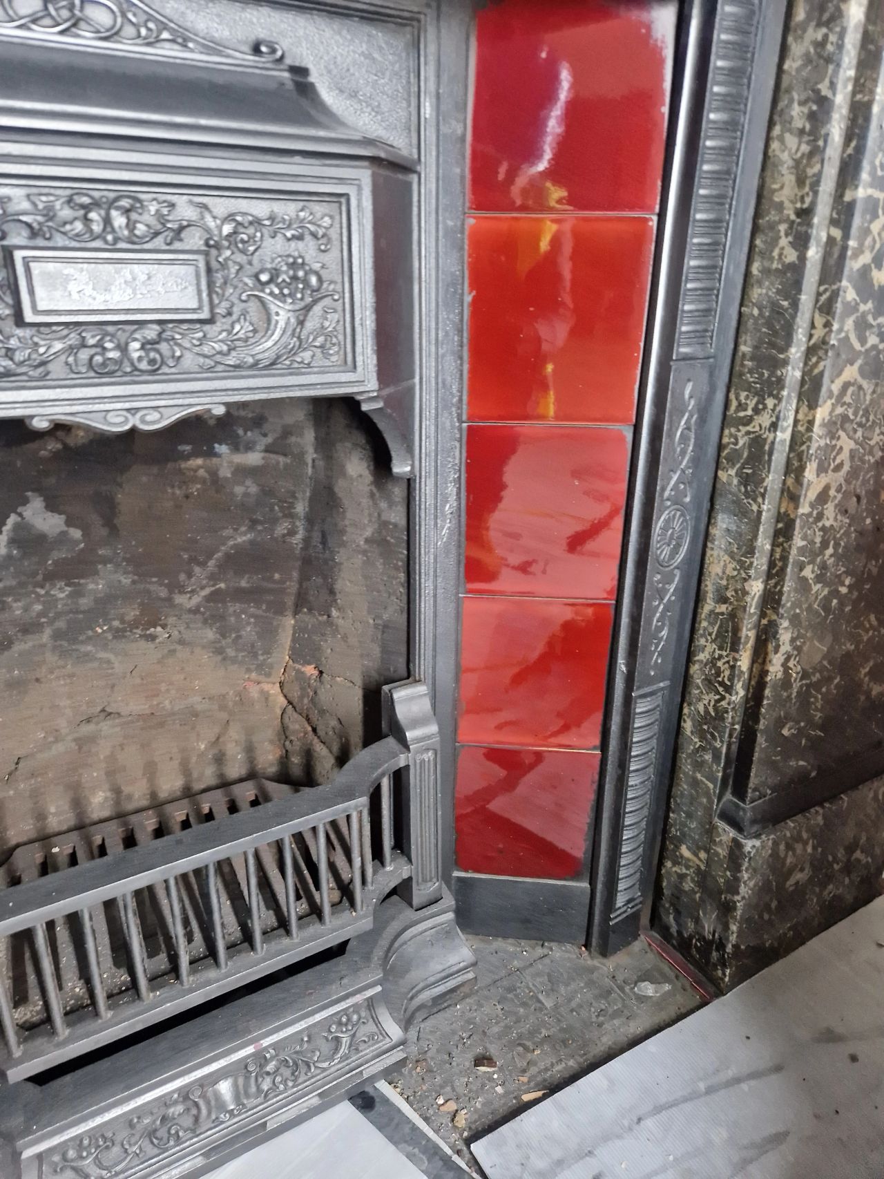 Restored red fireplace tiles alongside a cast iron and marble fire surround