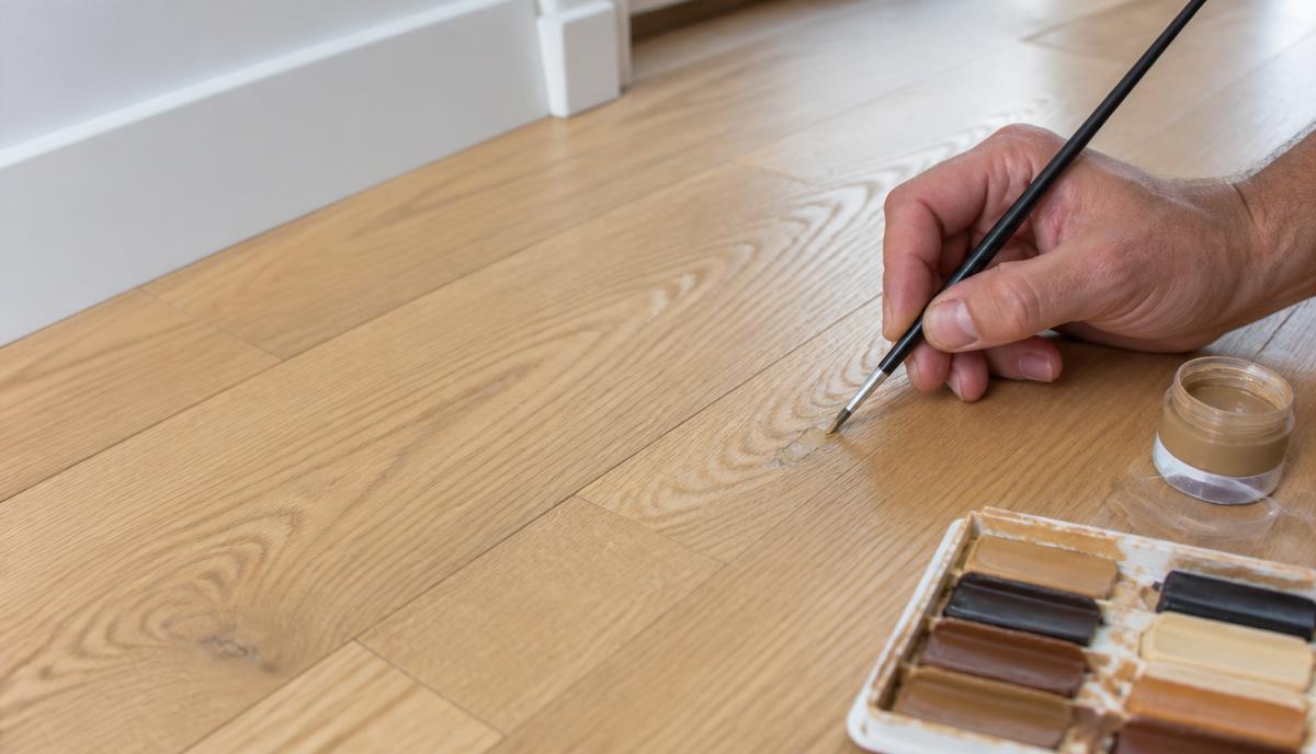 Illustrative localised colour repair to a scratched timber-effect floor.